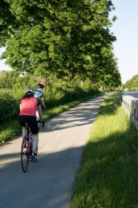 woman riding bicycle on path between green trees