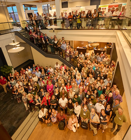 very large group posing for photo in two-story hotel lobby