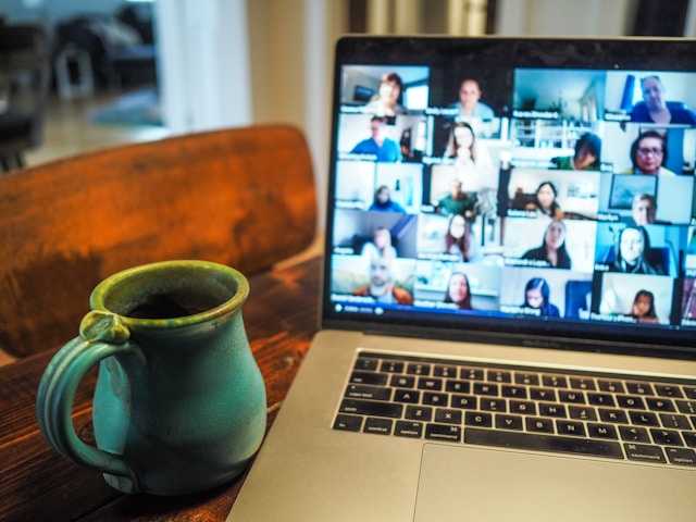 laptop screen showing online meeting next to a ceramic mug