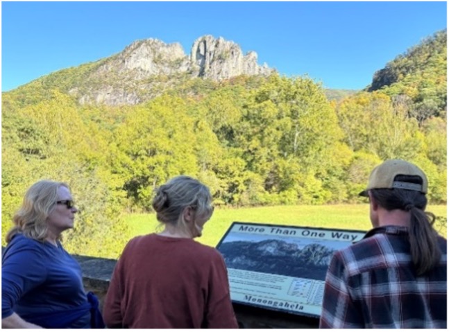 Three members of the group read an interpretive sign at a park